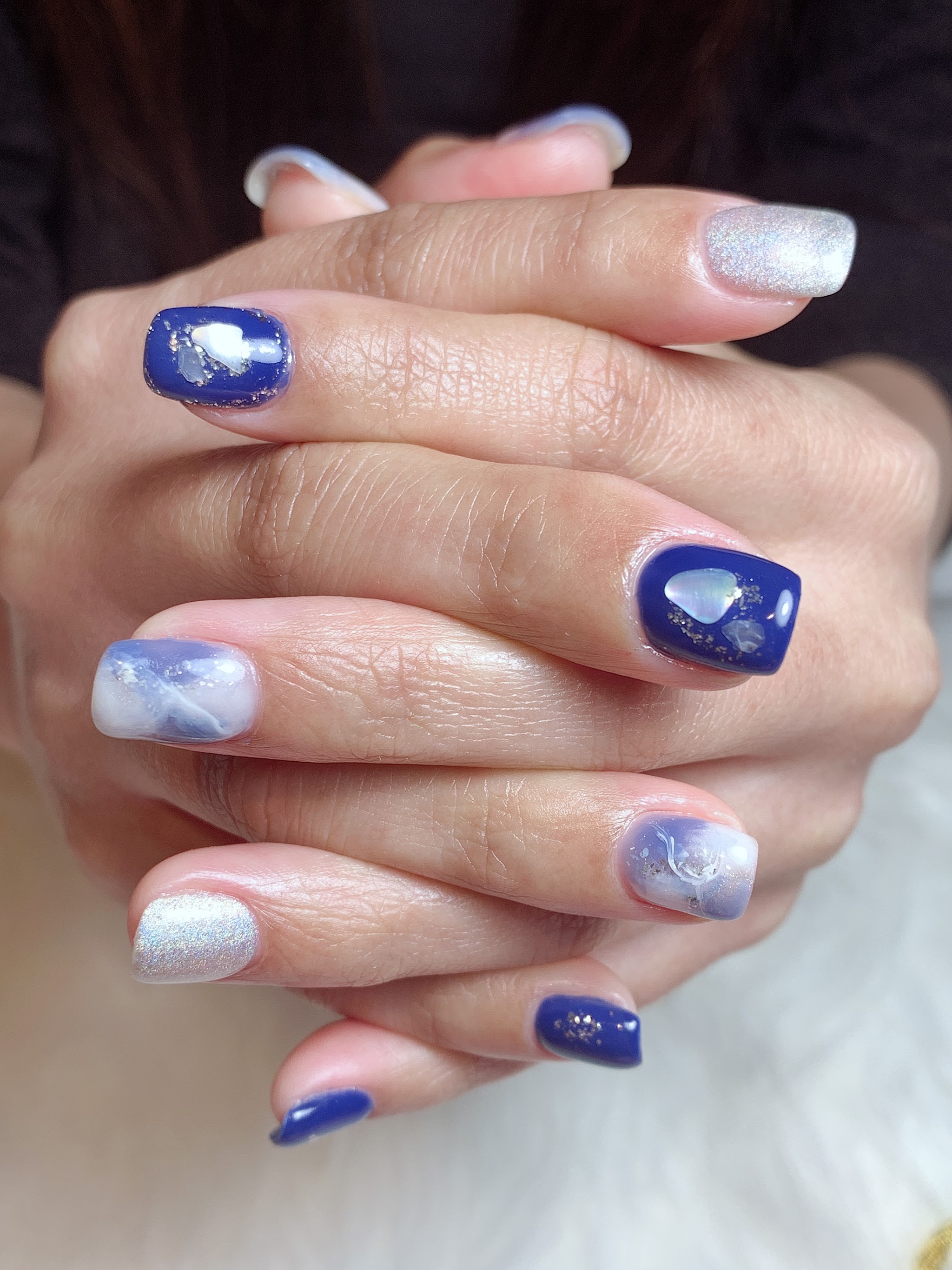 Nail art met blauw en parelwit marmer op gevouwen handen