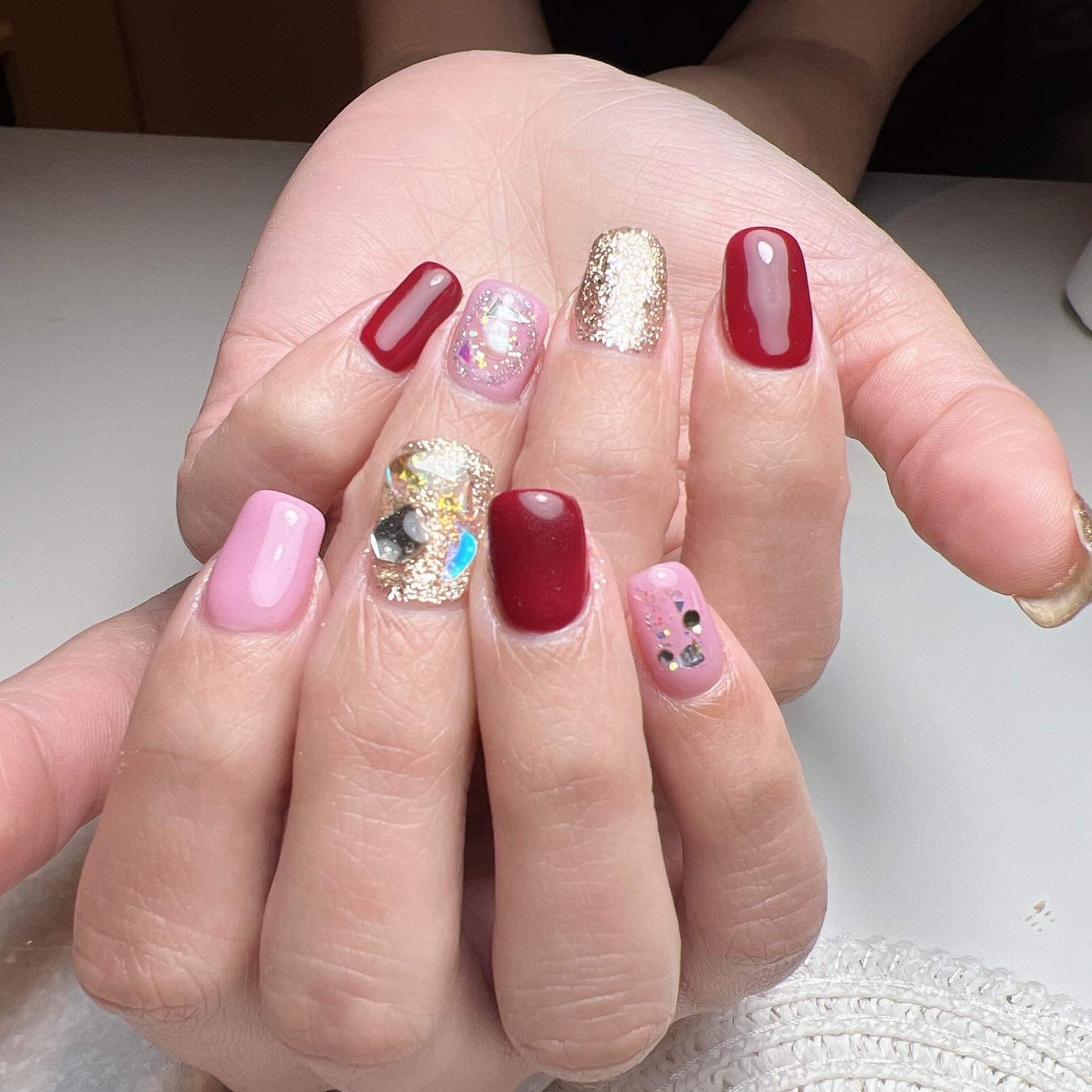 Rood, roze en goud met glitter en steentjes op een open hand