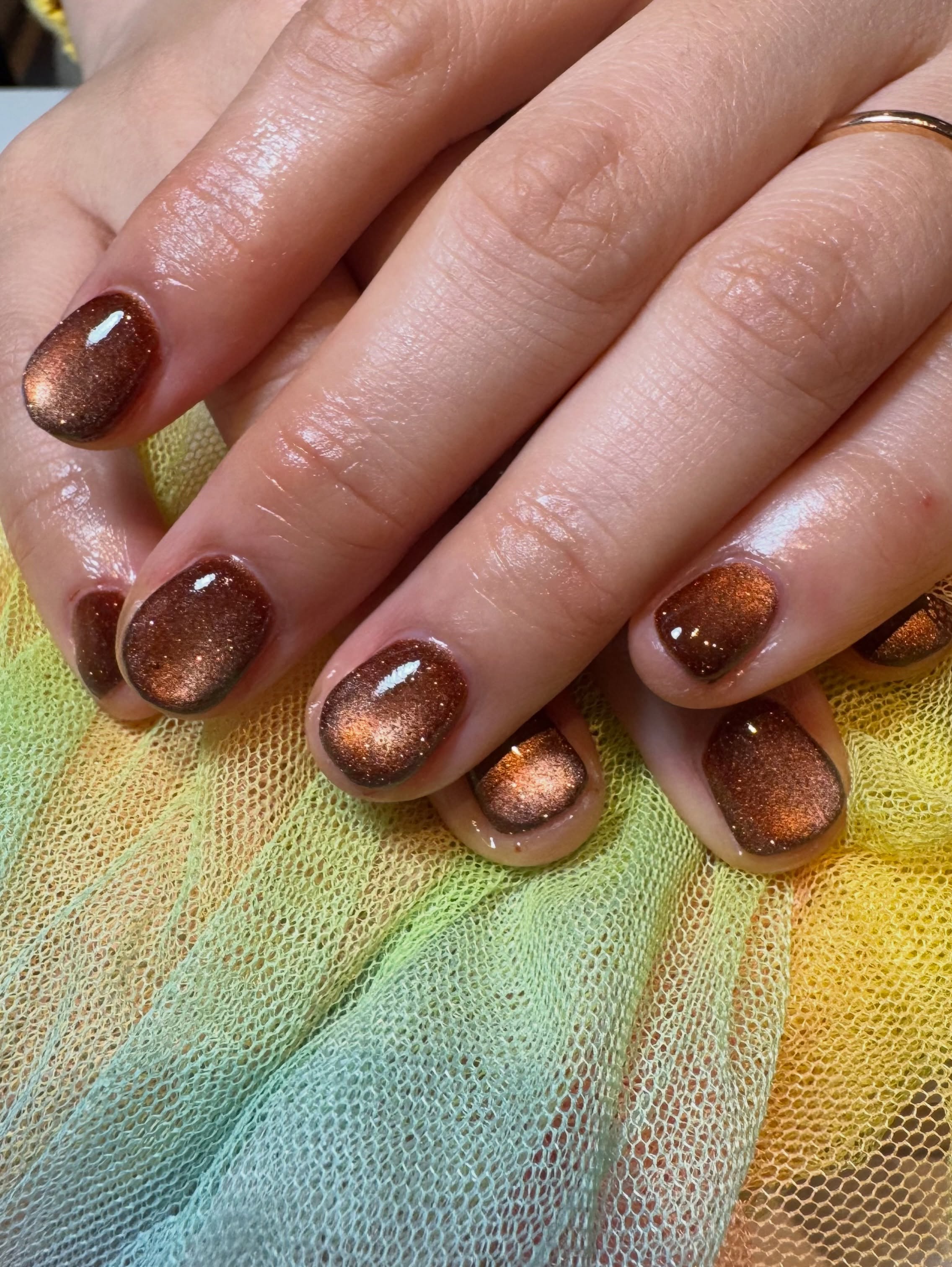 Cat eye gel in koper en bruin op korte nagels, boven roze en groene tule